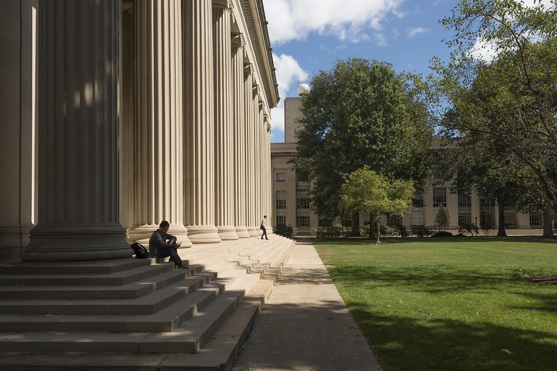 People sit on the steps adjoining Killian Court on a spring day.