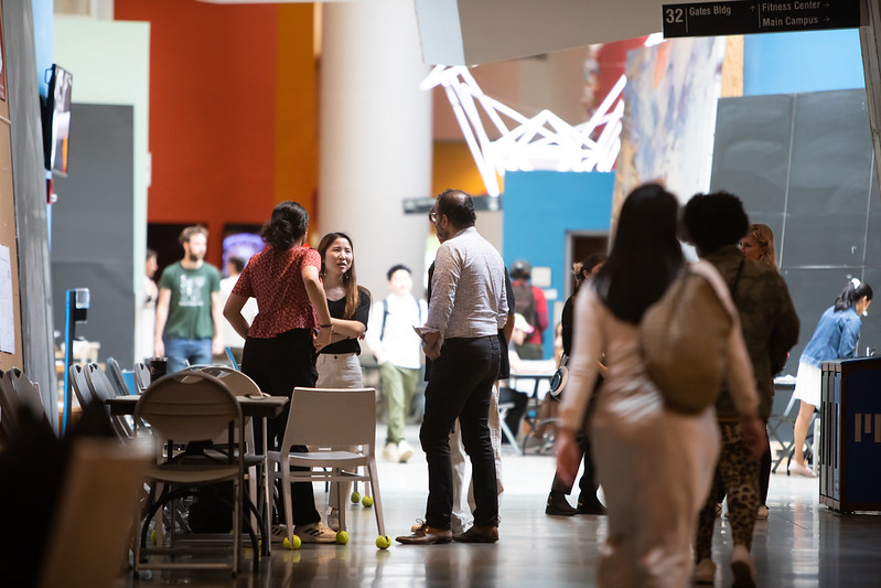 Students and faculty chat in a hall on campus.