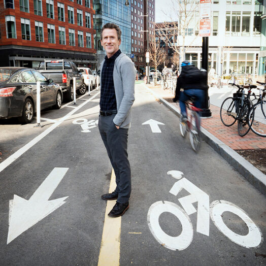 Chris Zegras stands amid a two-way bike path on a busy city corner