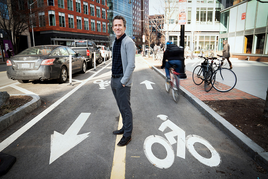 Chris Zegras stands amid a two-way bike path on a busy city corner